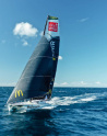 Le bateau de Violette Dorange, DeVenir, en pleine mer. On voit le logo d'Apprentis d'Auteuil en haut de la grand-voile et celui de MacDonalds en bas.